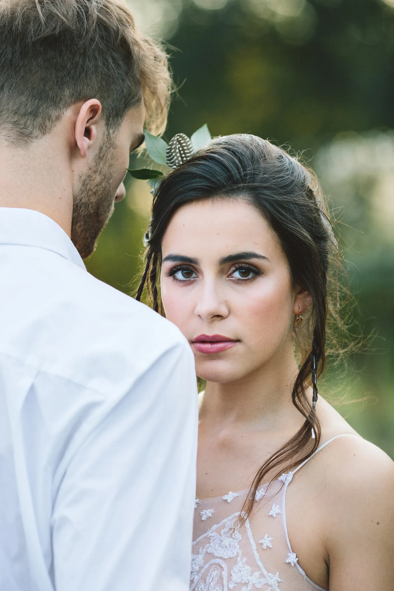 Portrait of the bride in a white dress with the groom in an open white shirt in the foreground