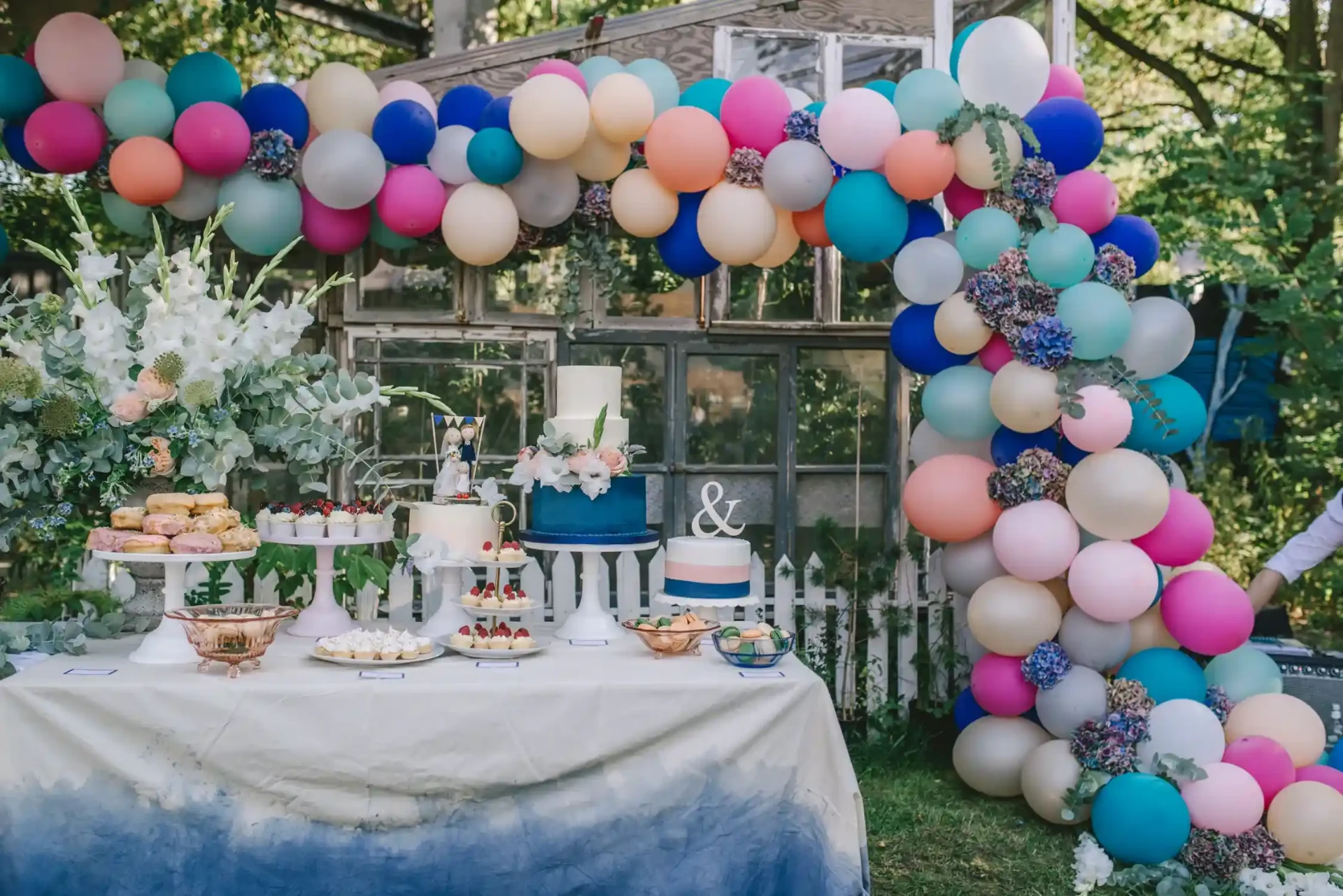 Festlich dekorierter Tisch vor einer Wand aus bunten Luftballons