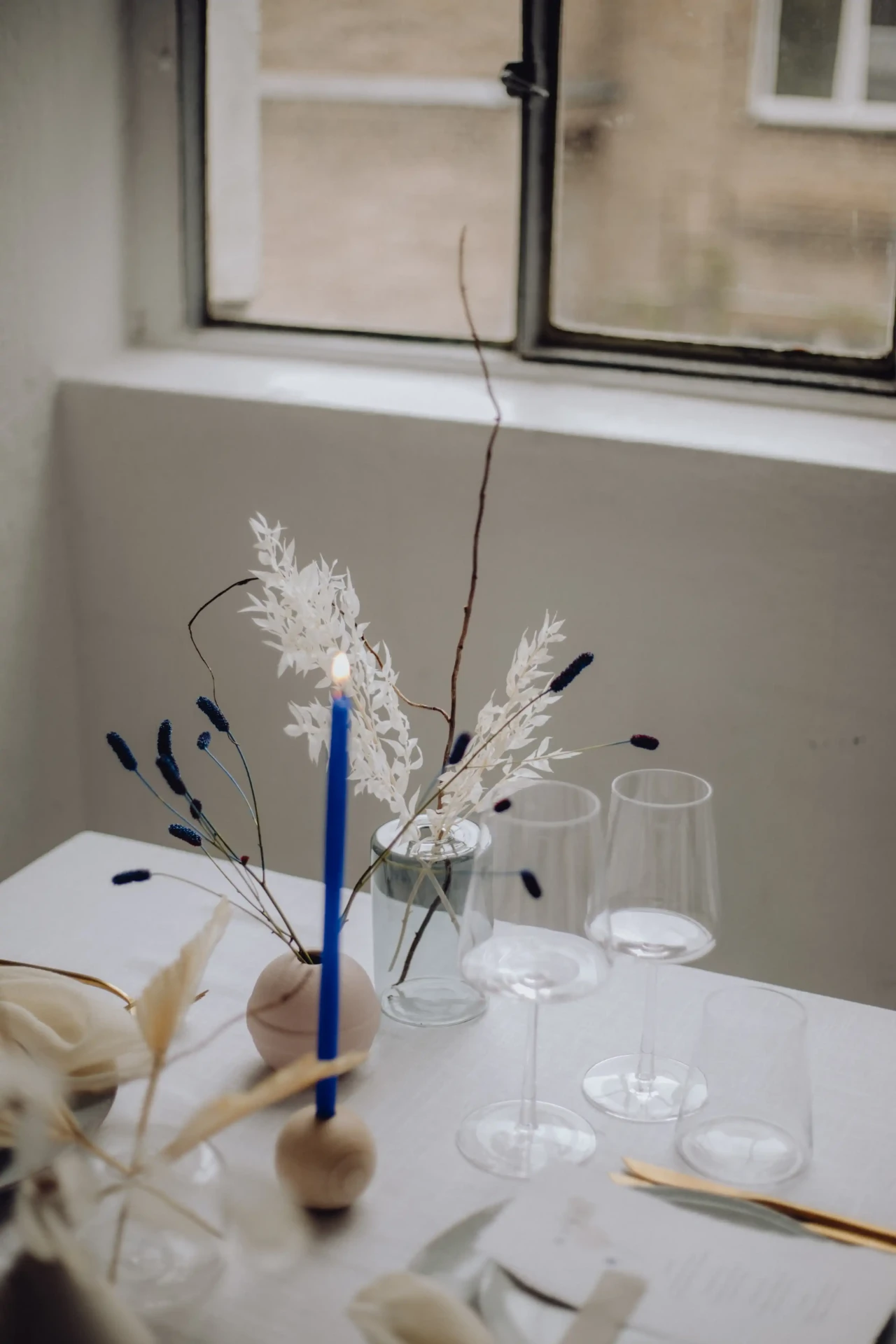 Detail of white table decor with blue cutlery and flowers