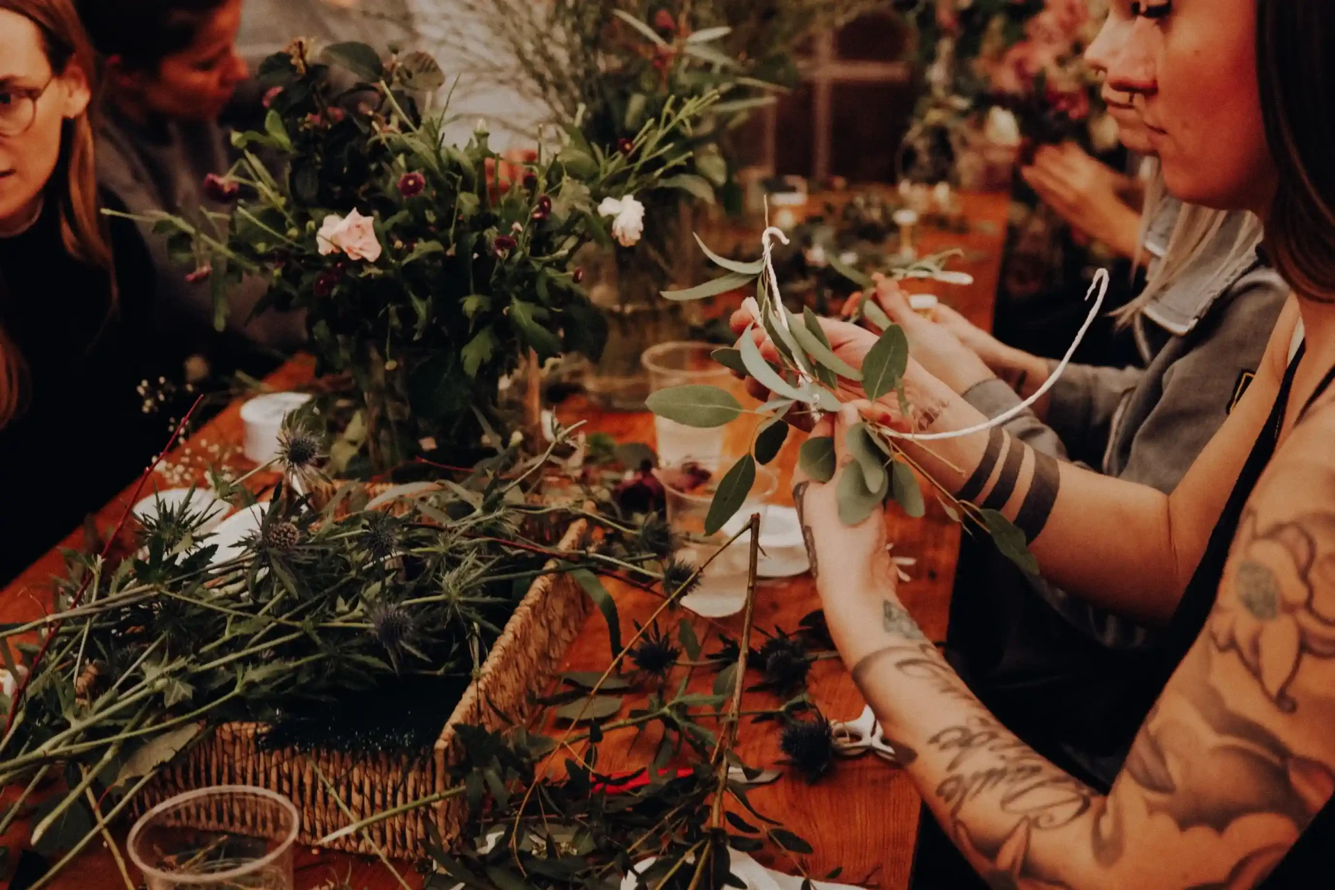Hands arranging flowers and decorations on a table