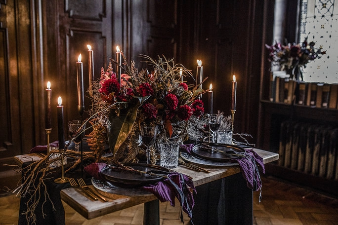 Festlich gedeckte Tafel mit Kerzen, Blumen und dunklen Beerentönen