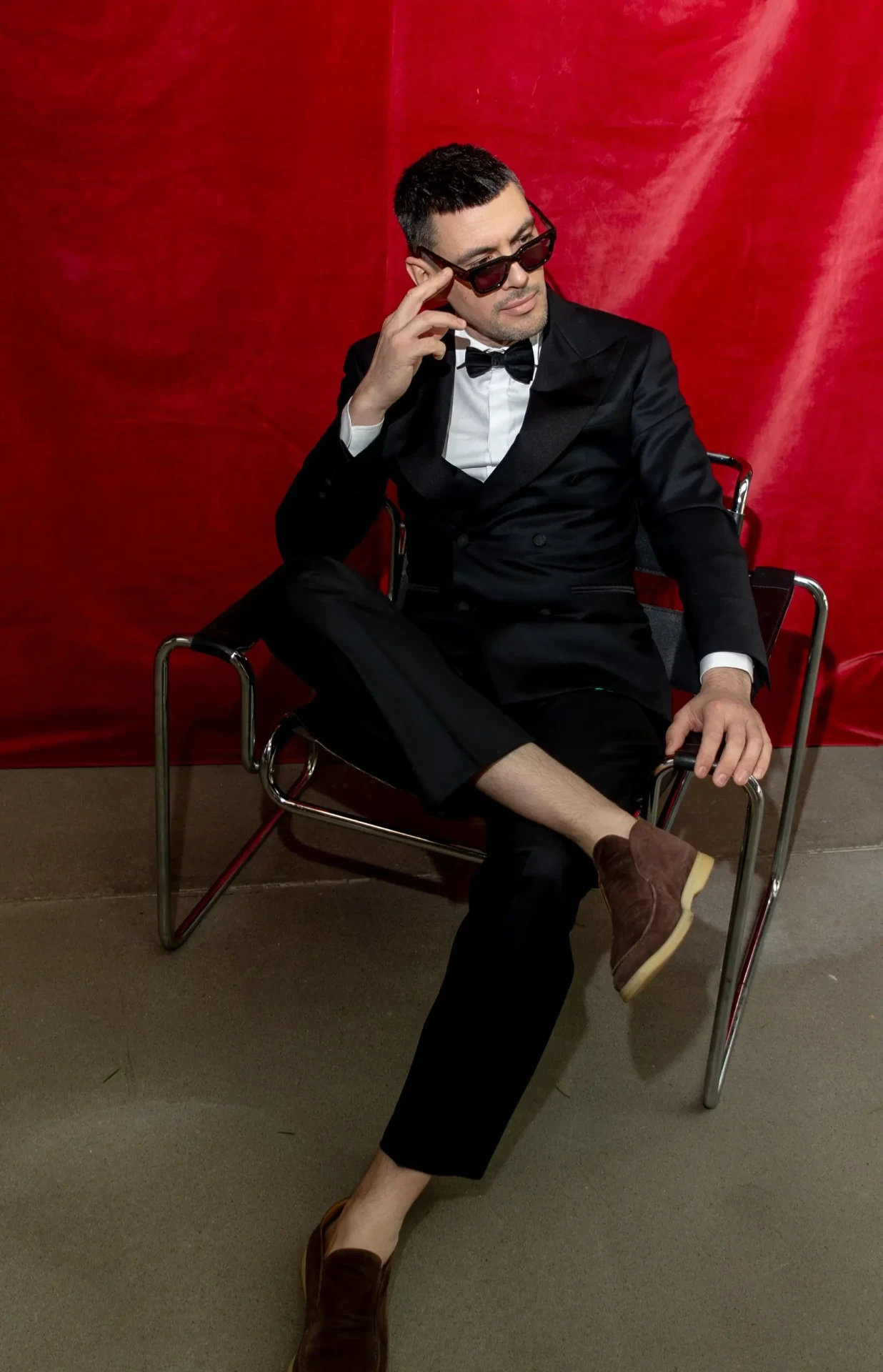 Man in a suit seated in front of a red backdrop