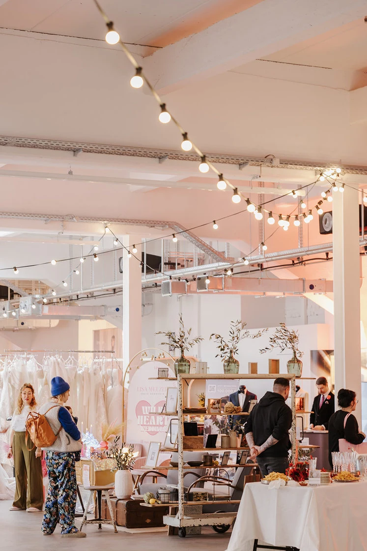 Bright event space with long tables and string lights overhead