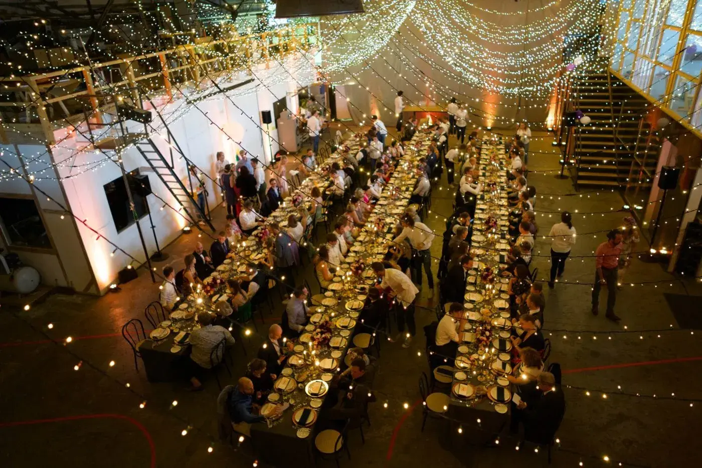 Aerial view of a long wedding table with guests and warm lighting