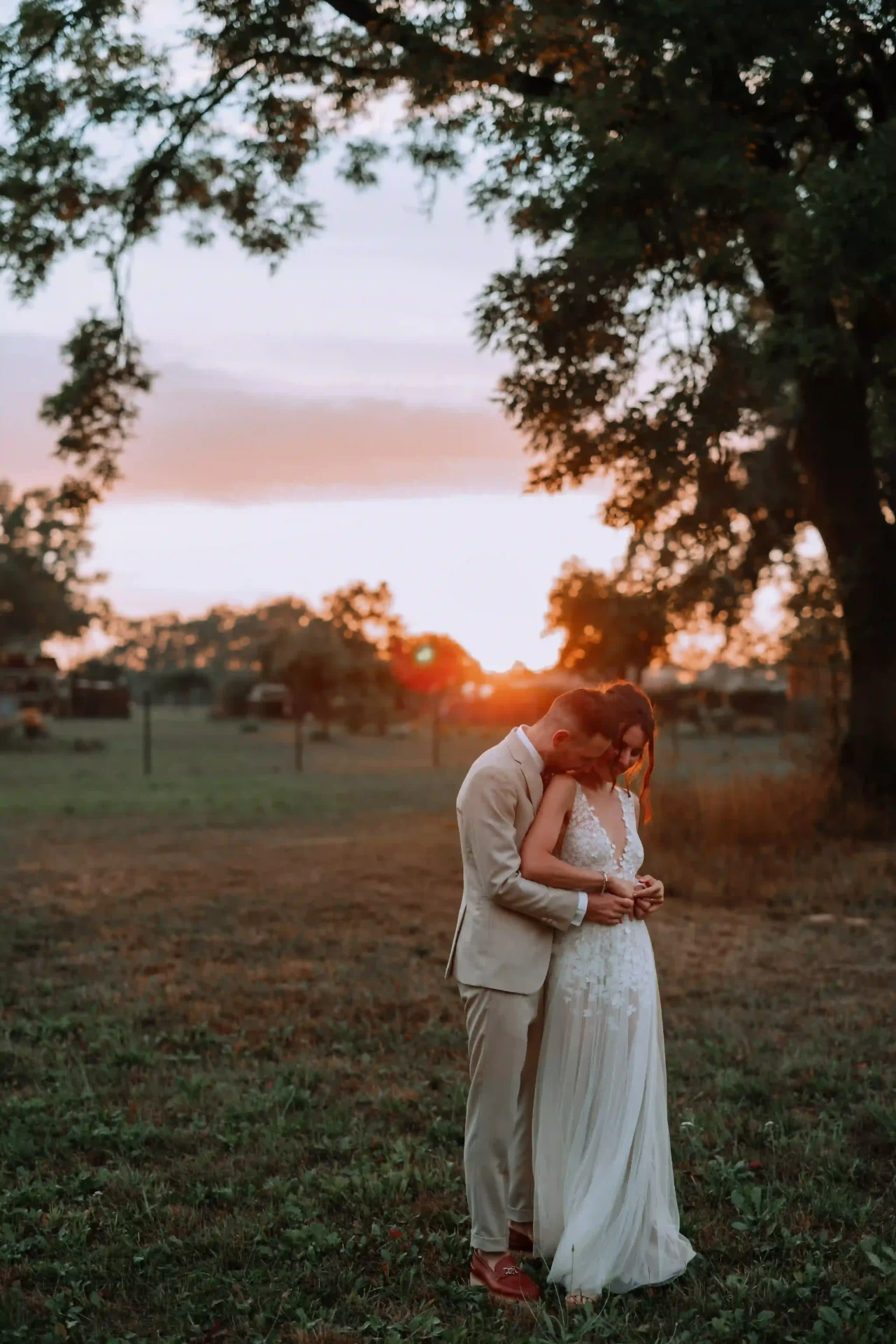Bride and groom embracing in backlight at sunset
