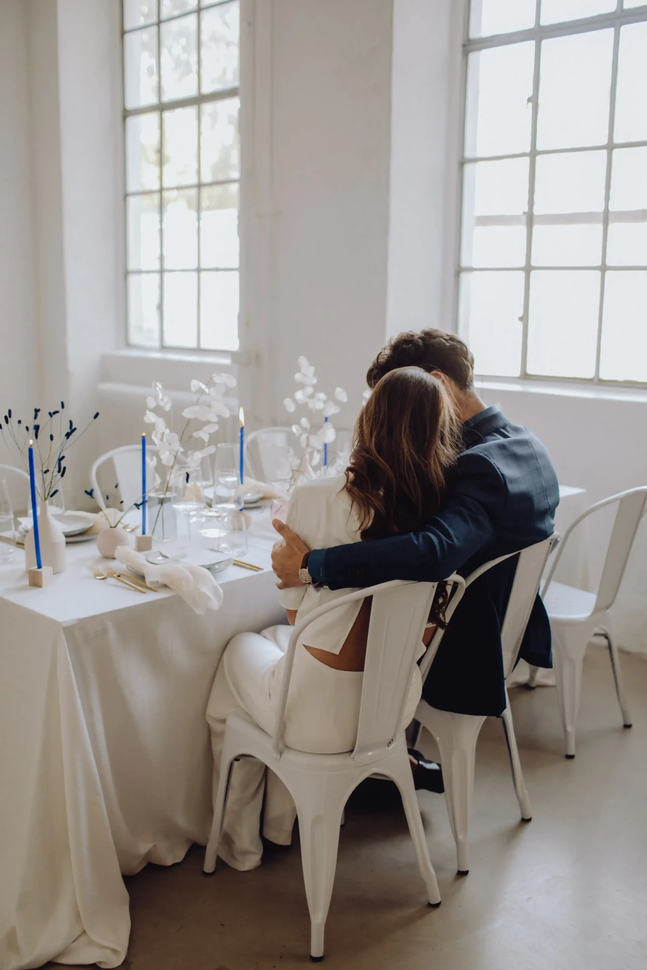 Wedding couple seated at the wedding table in front of tall windows