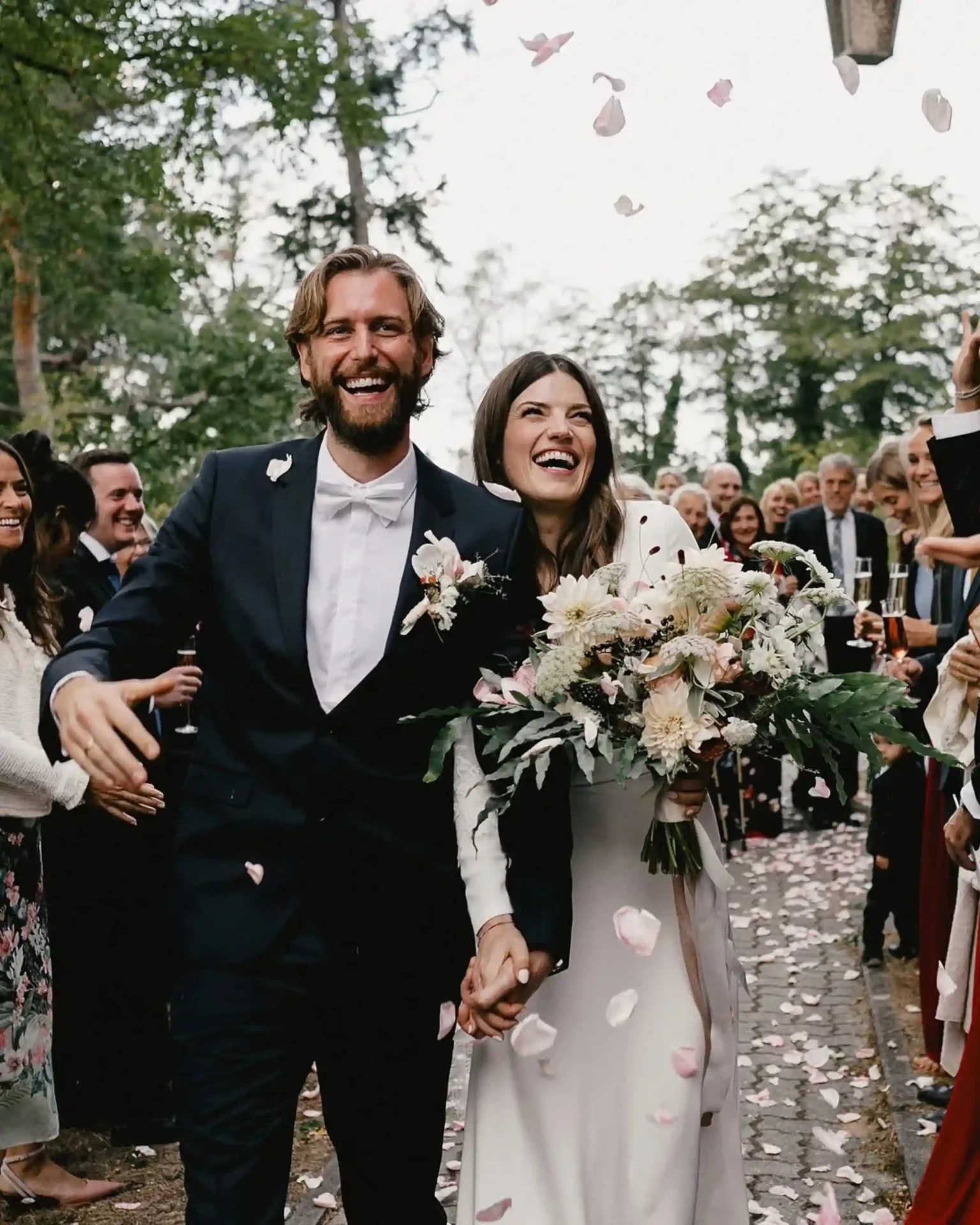 Bride and groom laughing during their wedding celebration as confetti falls around them