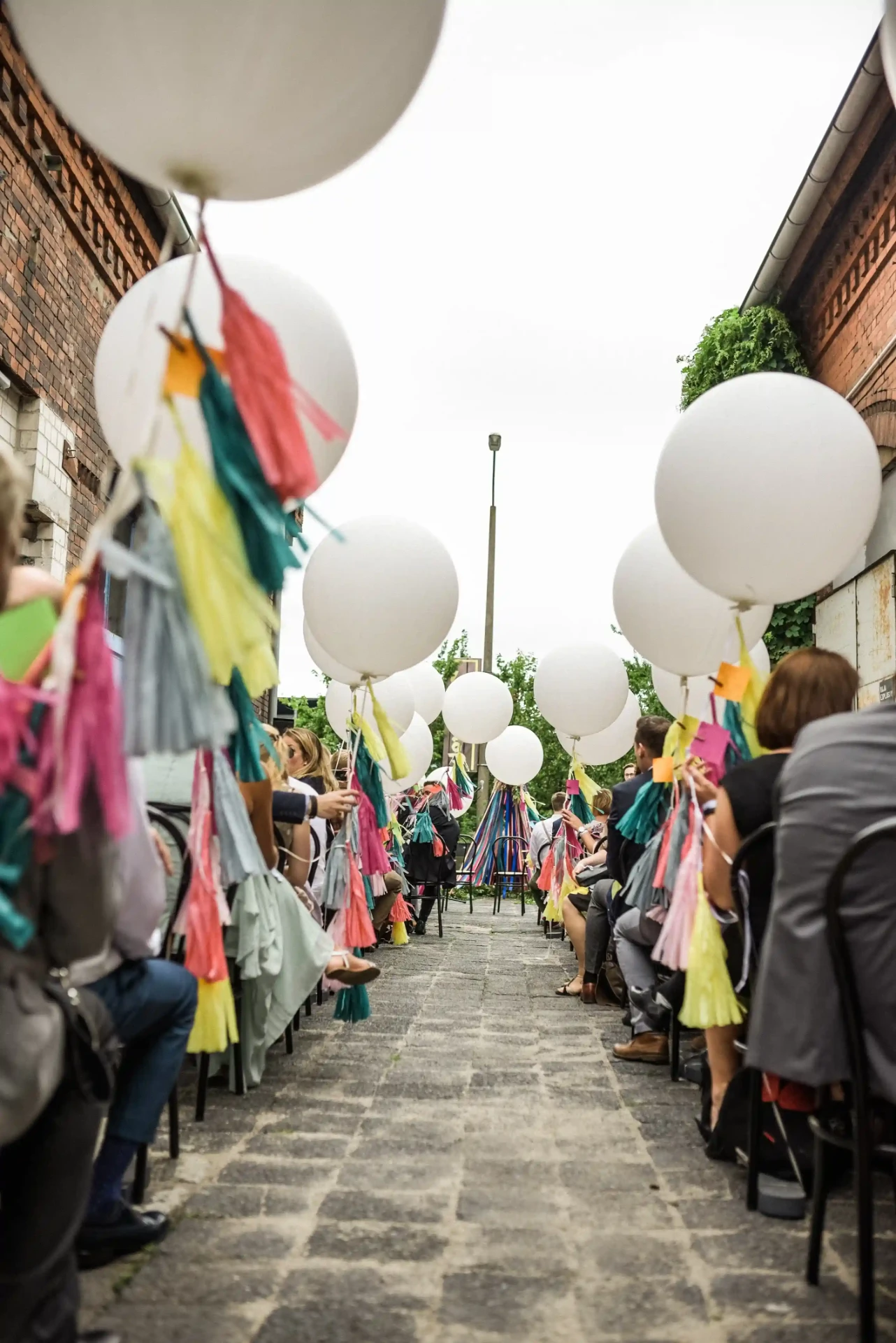 Wedding guests walking through an aisle of white and colourful balloons