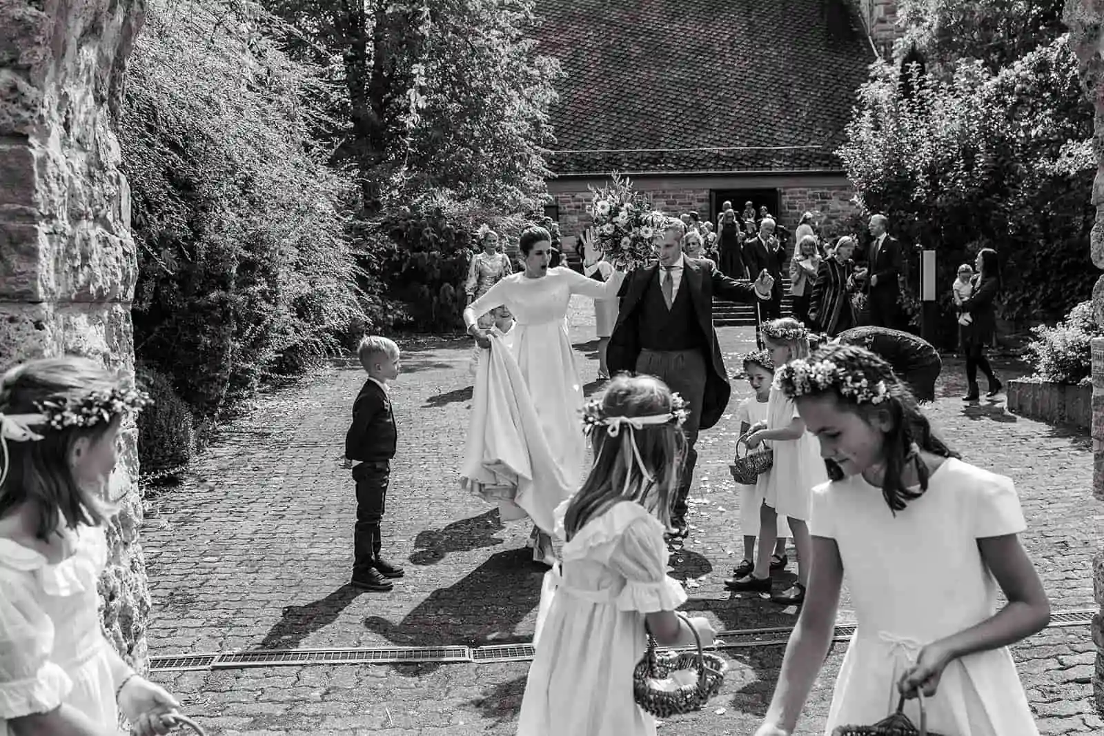 Black-and-white photograph of wedding guests in a garden among trees