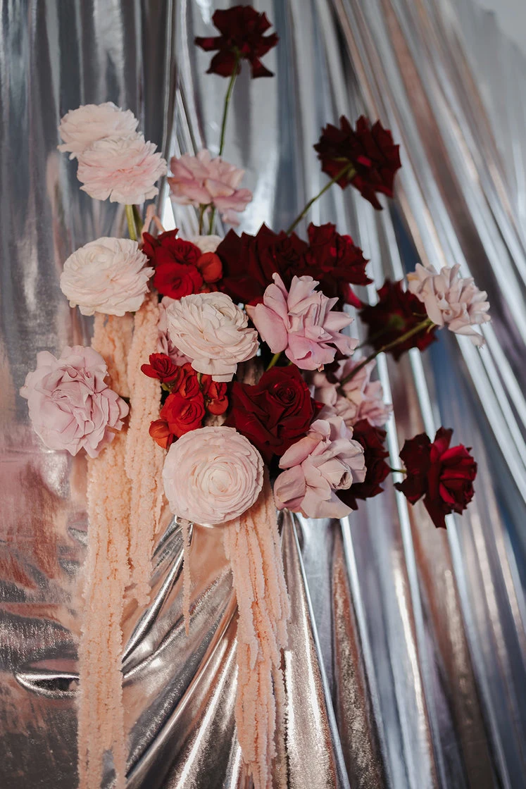Floral arrangement with white and pink flowers in front of a curtain