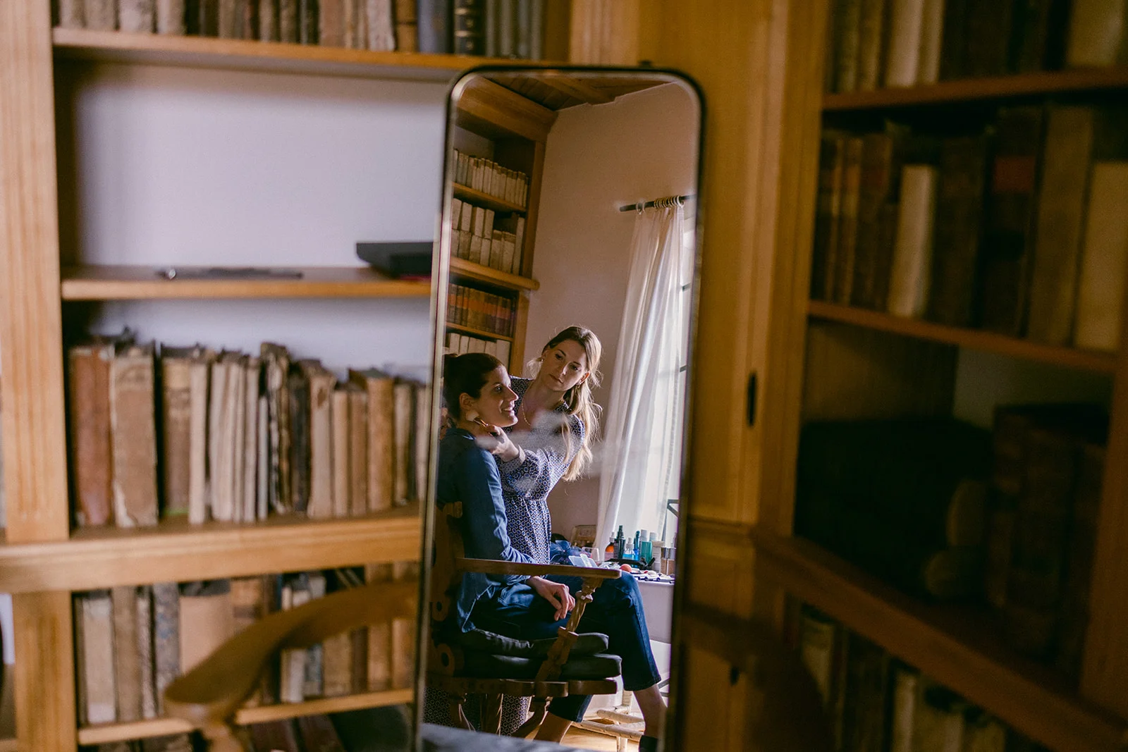 Person sitting in front of a bookcase and a large mirror