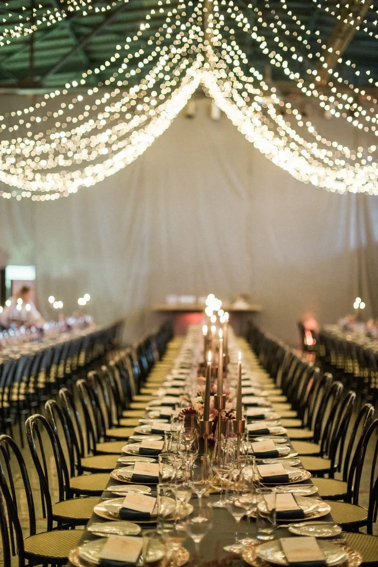Long wedding table with a fabric installation and warm lighting