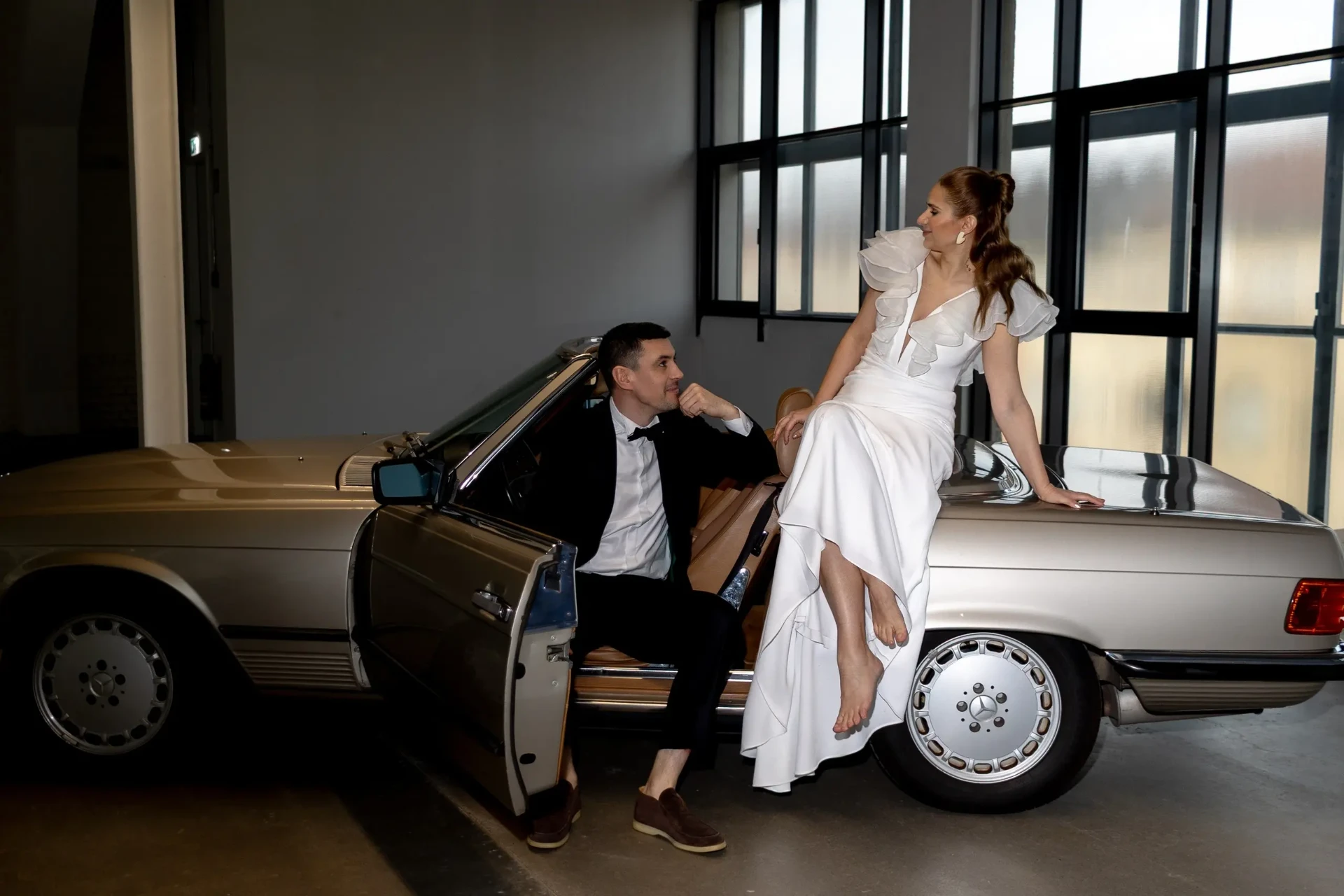 Wedding couple beside a convertible indoors