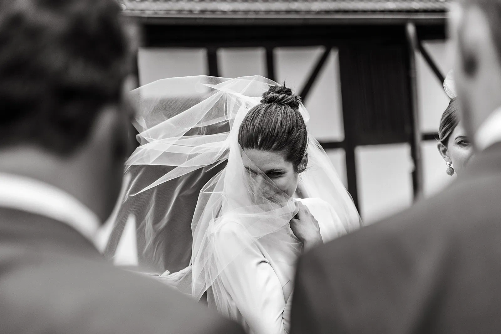 Black-and-white portrait of the bride behind her sheer veil