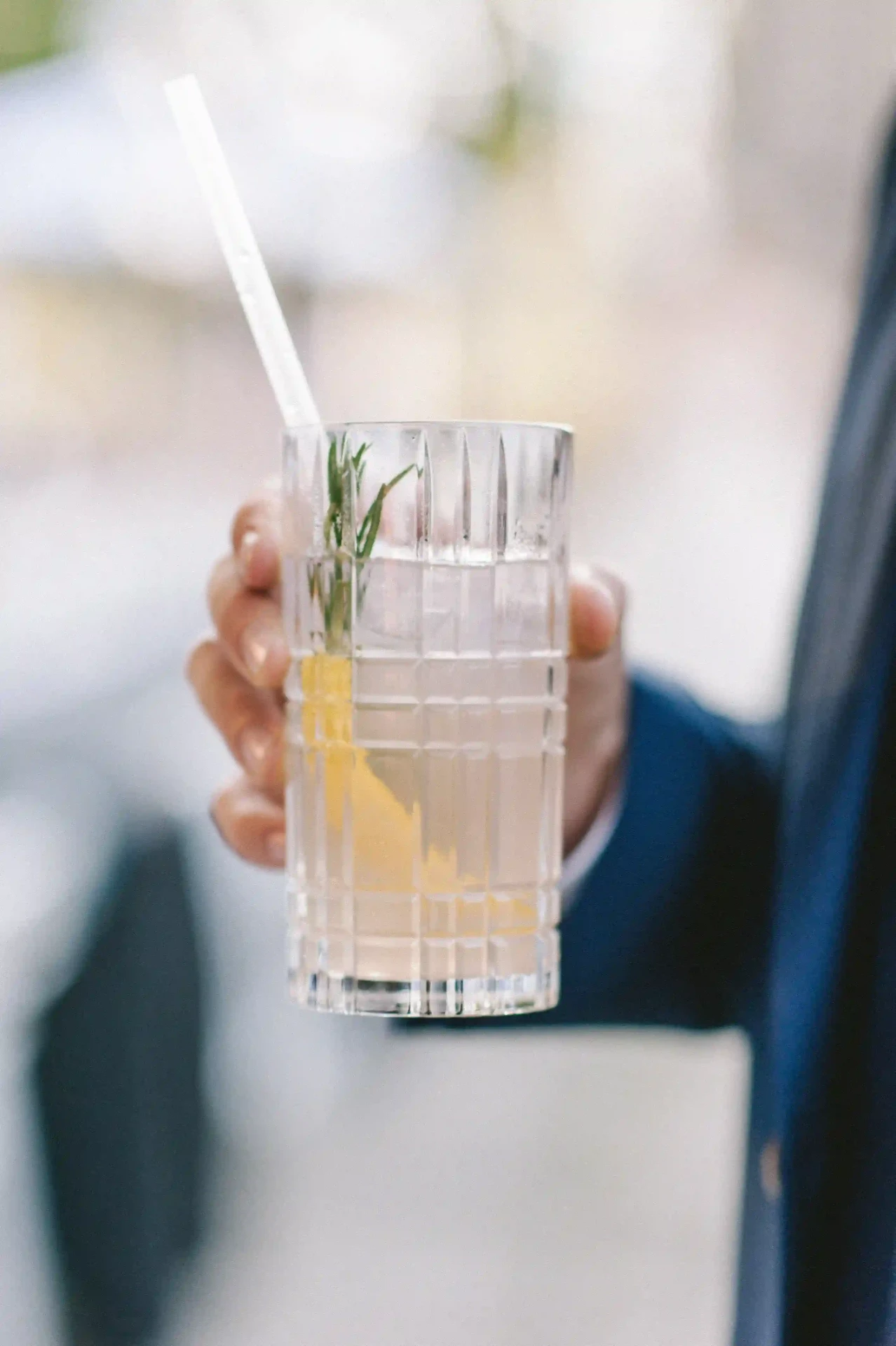 Hand hält ein Glas vor hellem Hintergrund
