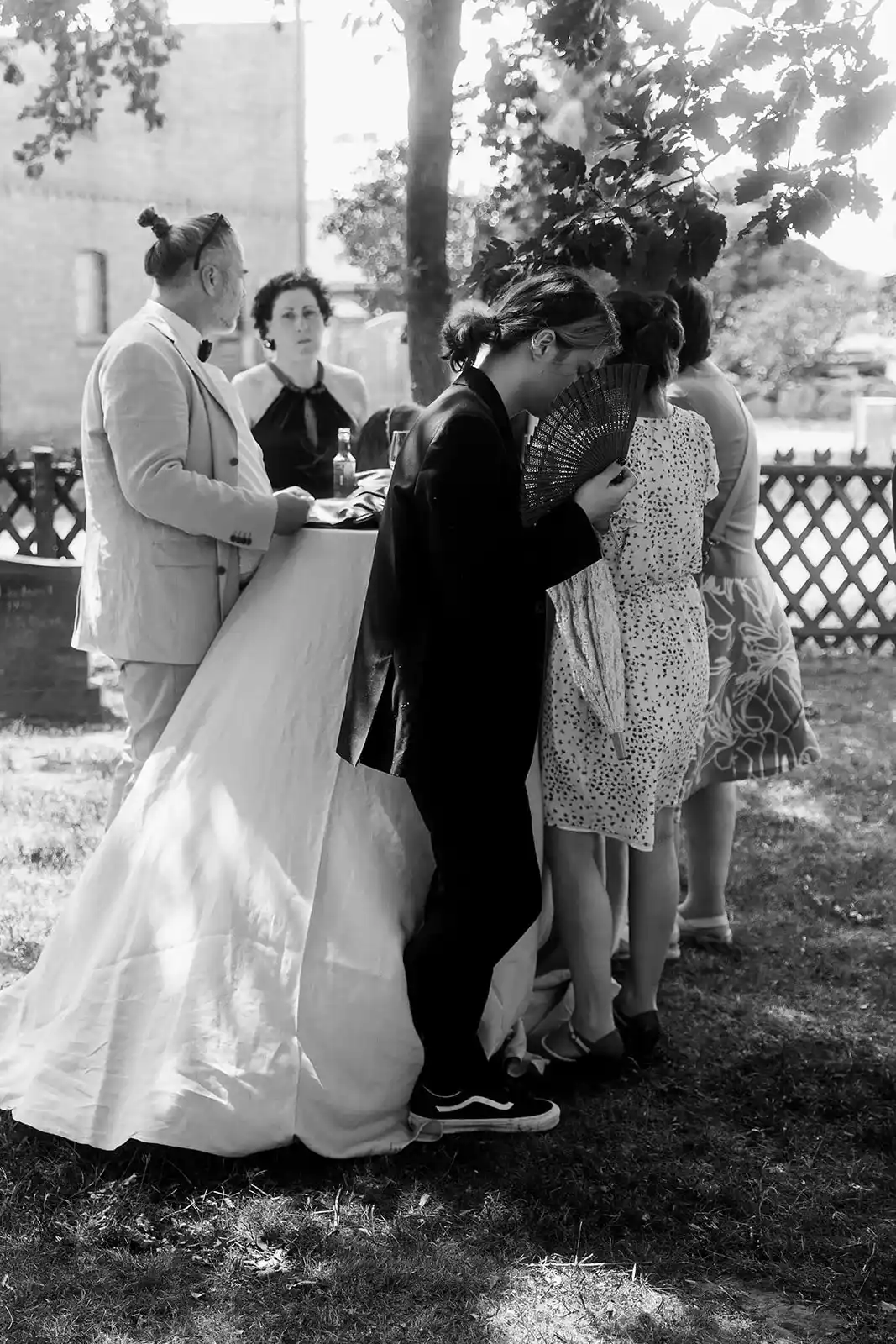 Black-and-white photograph of the wedding couple with guests outdoors