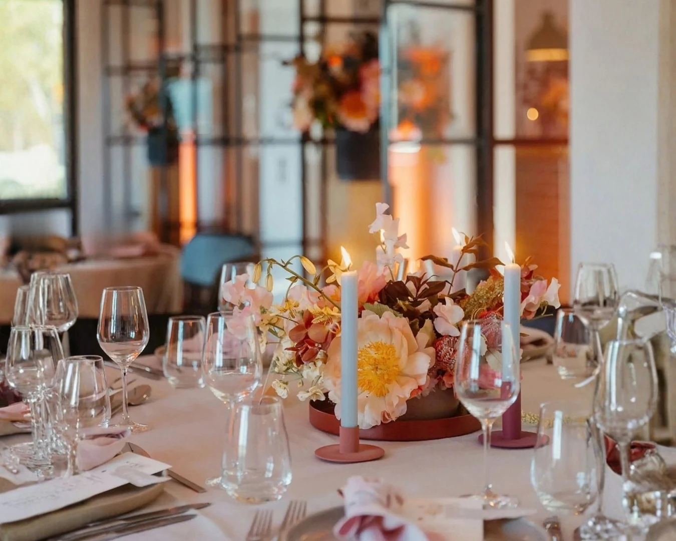 Modern minimalist wedding table setting with sculptural floral design, candles and elegant glassware
