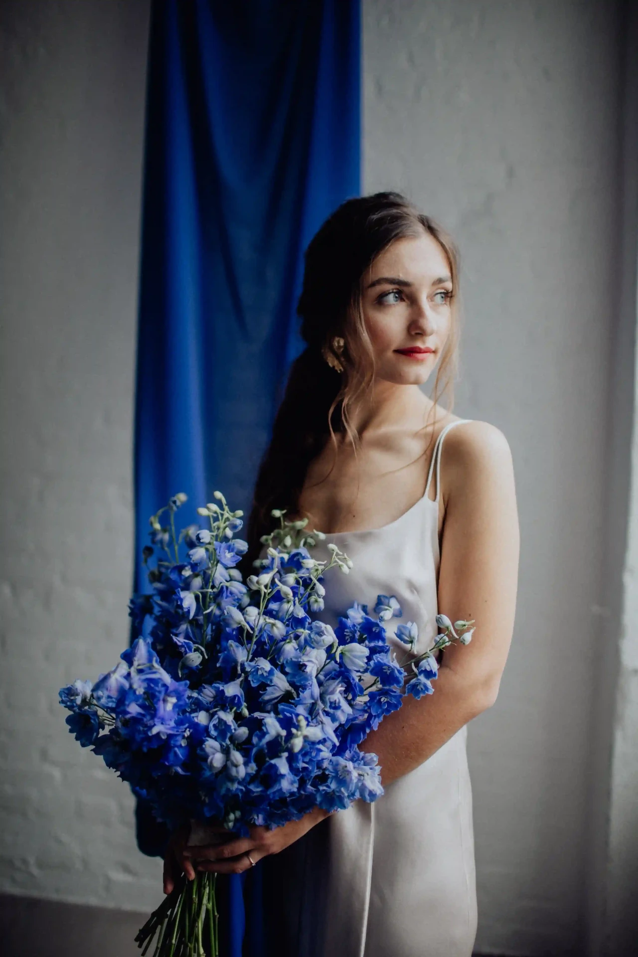 Bride in a simple white dress holding a blue bouquet