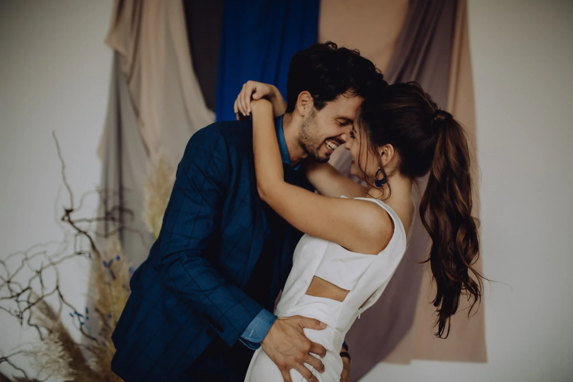 Wedding couple dancing closely together in front of blue curtains