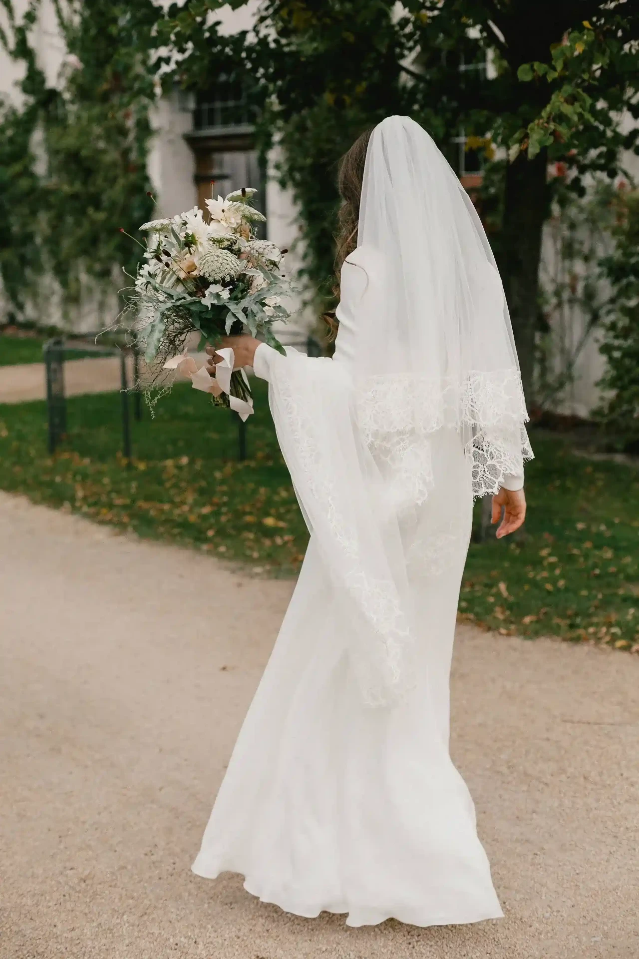 Bride in a white wedding dress walking along a garden path