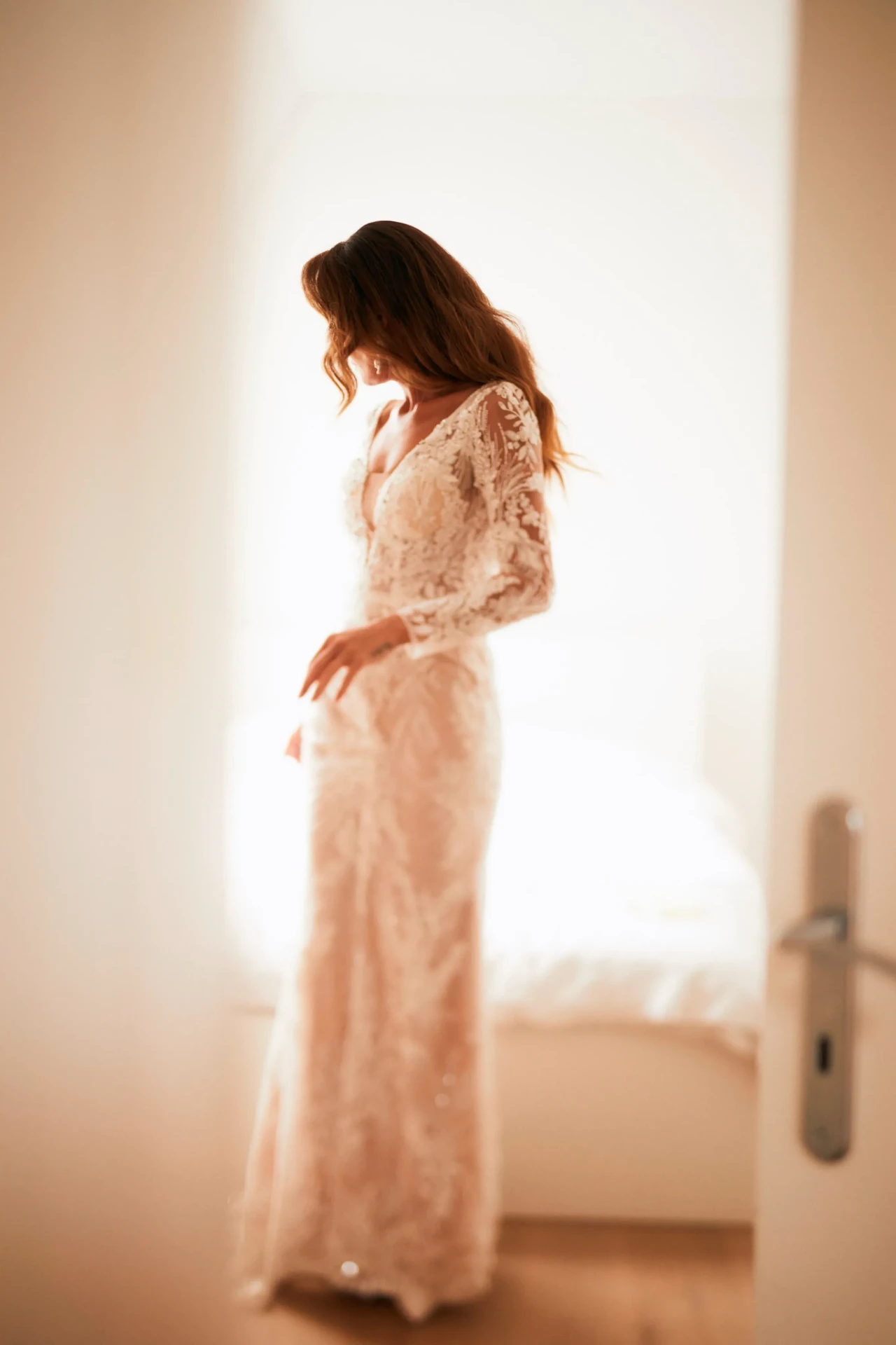 Bride in a white dress standing in profile in a bright interior