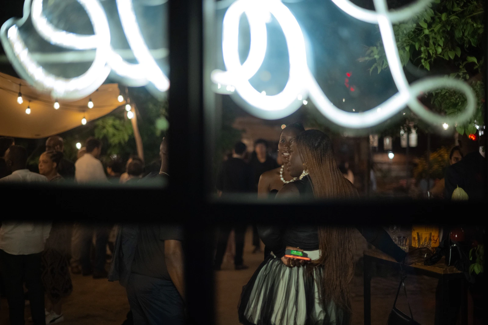 Neon lettering in a window reflecting the wedding celebration at night