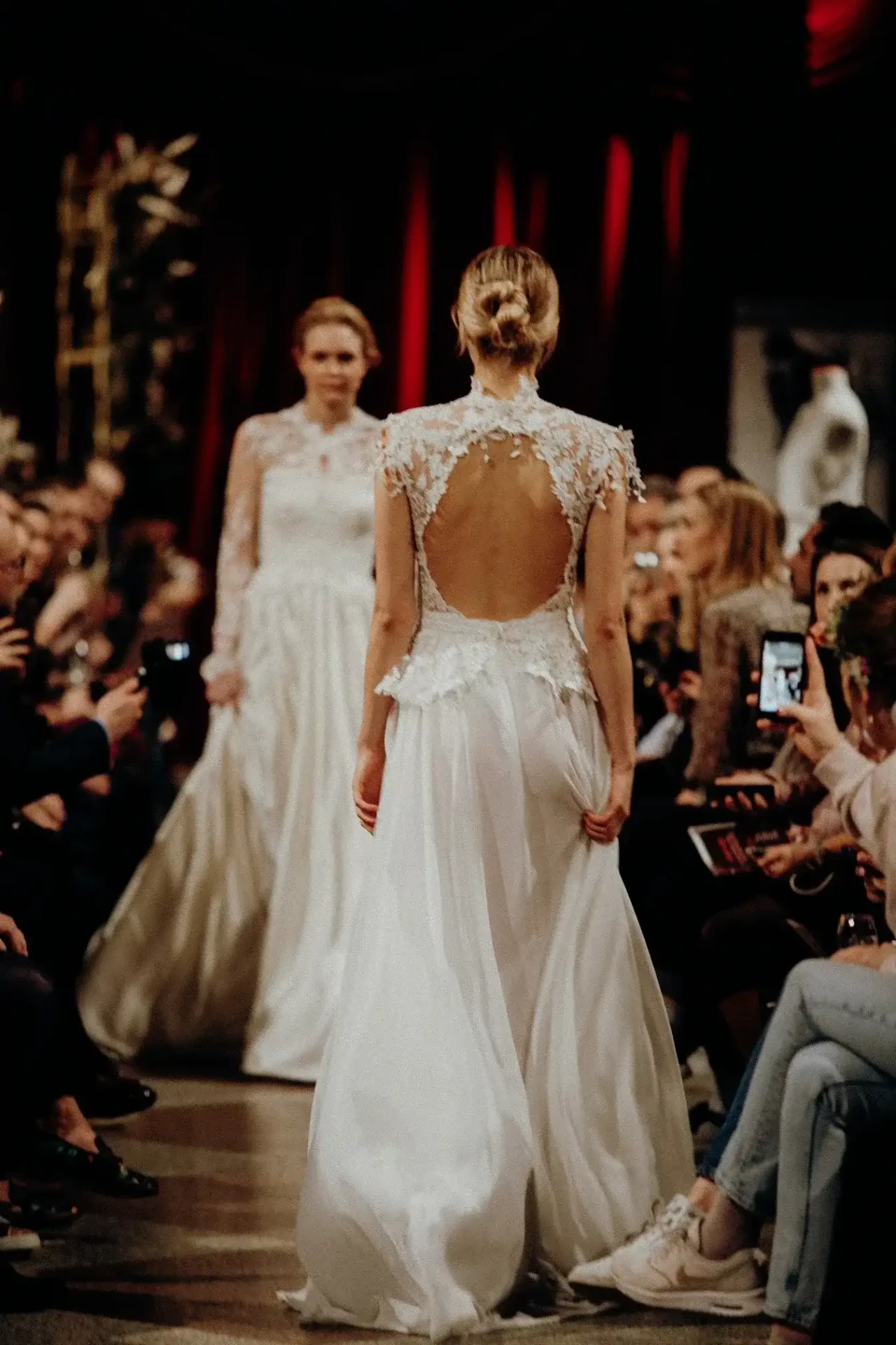 Models in wedding fashion on a runway against a dark background