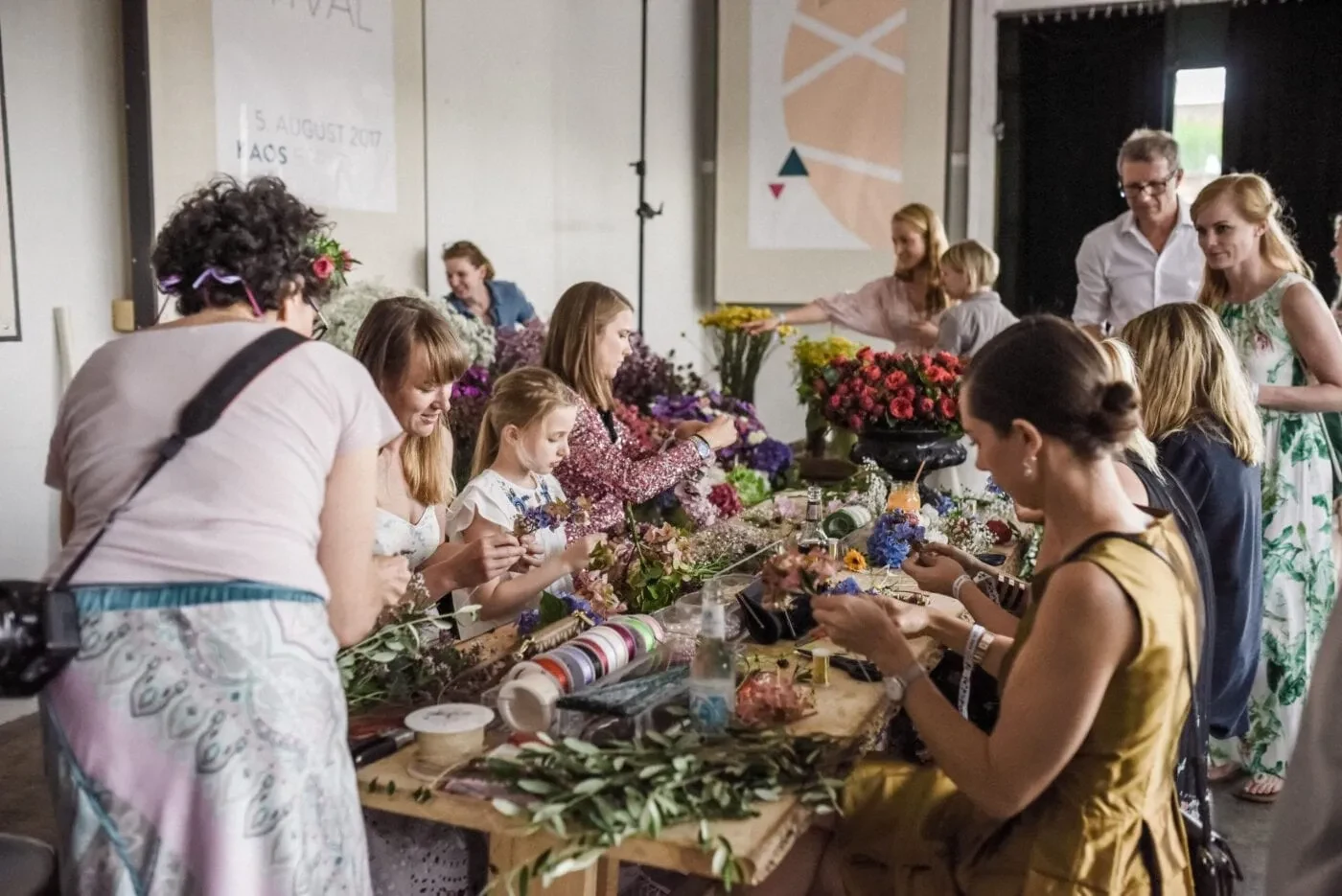 Guests seated at a long table making flower crowns together
