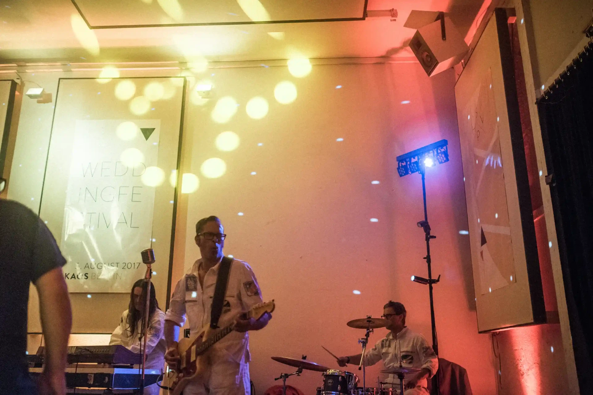 Musicians performing at a wedding celebration in front of an illuminated wall