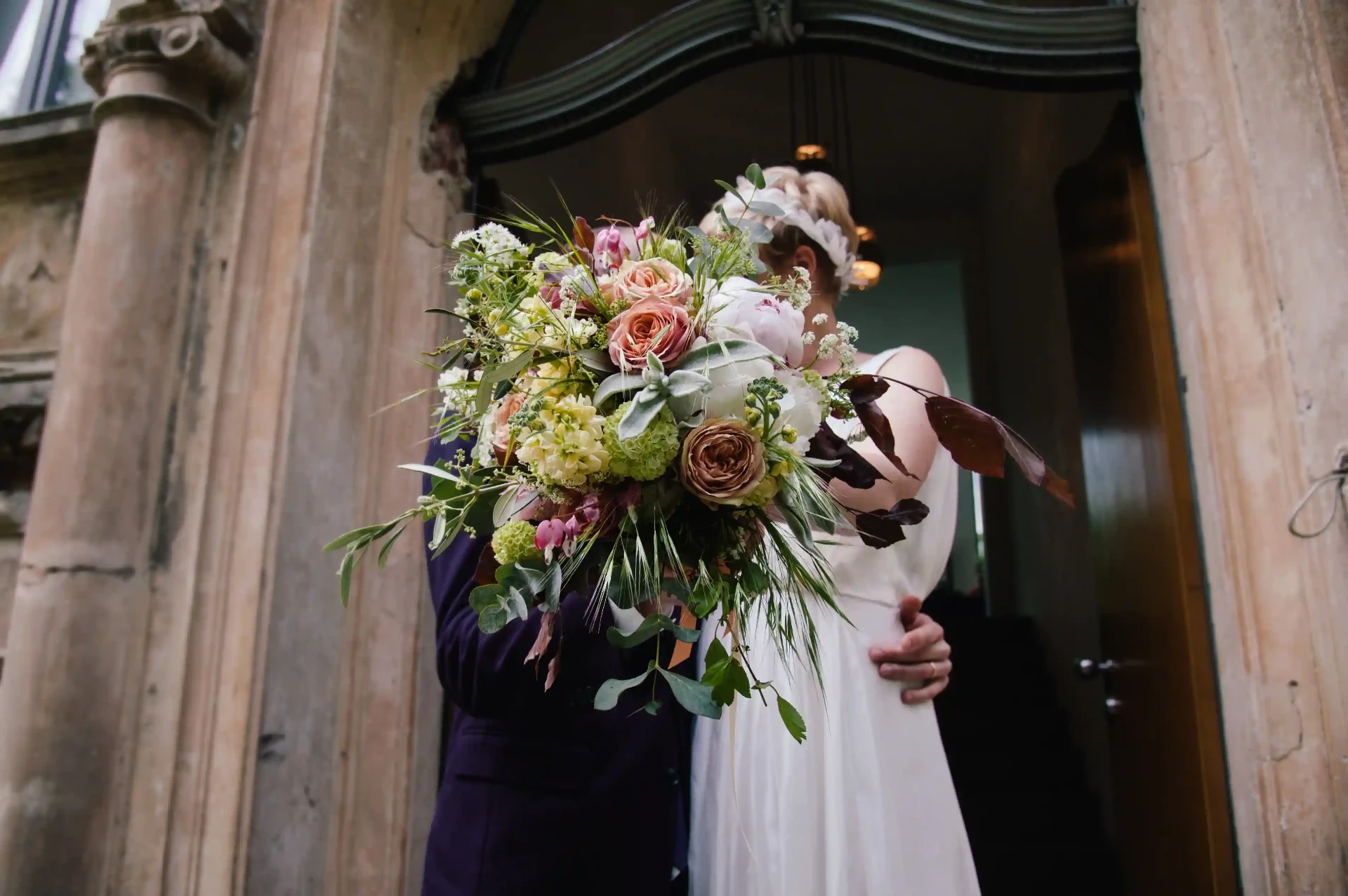 Colourful bridal bouquet in front of a historic entrance