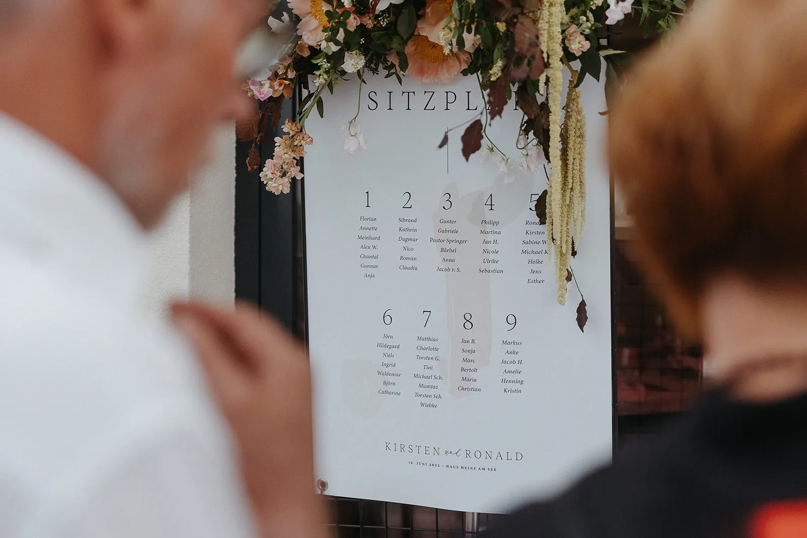 Hand holding a wedding card in front of a floral arrangement