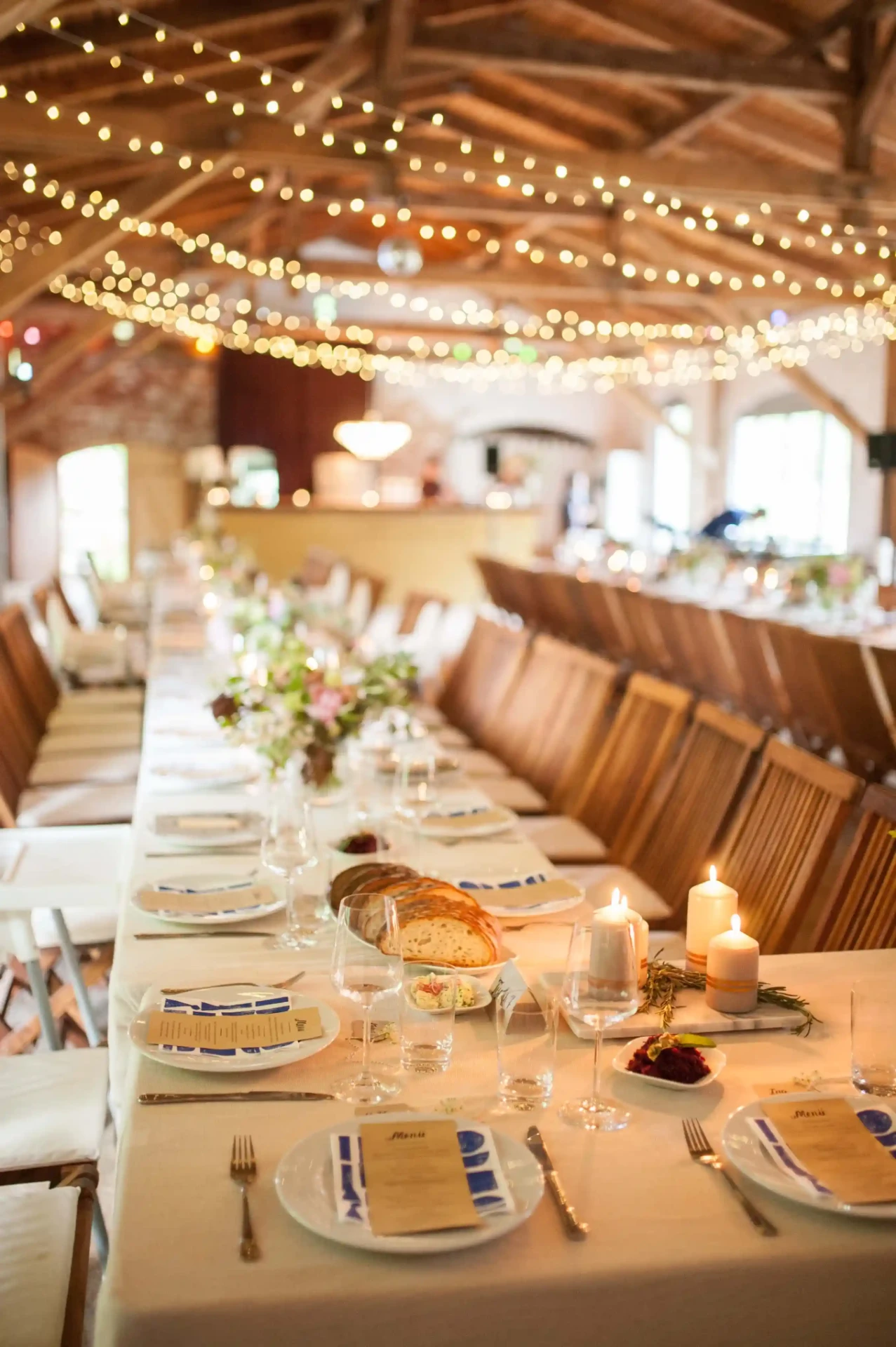 Festive dining table in a rustic barn with wooden beams and string lights