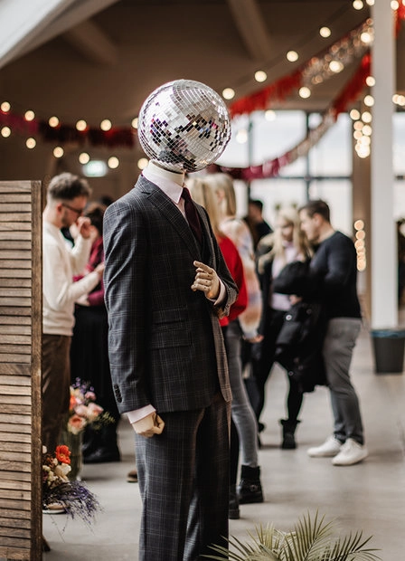 Visitors among exhibition stands beneath a disco ball