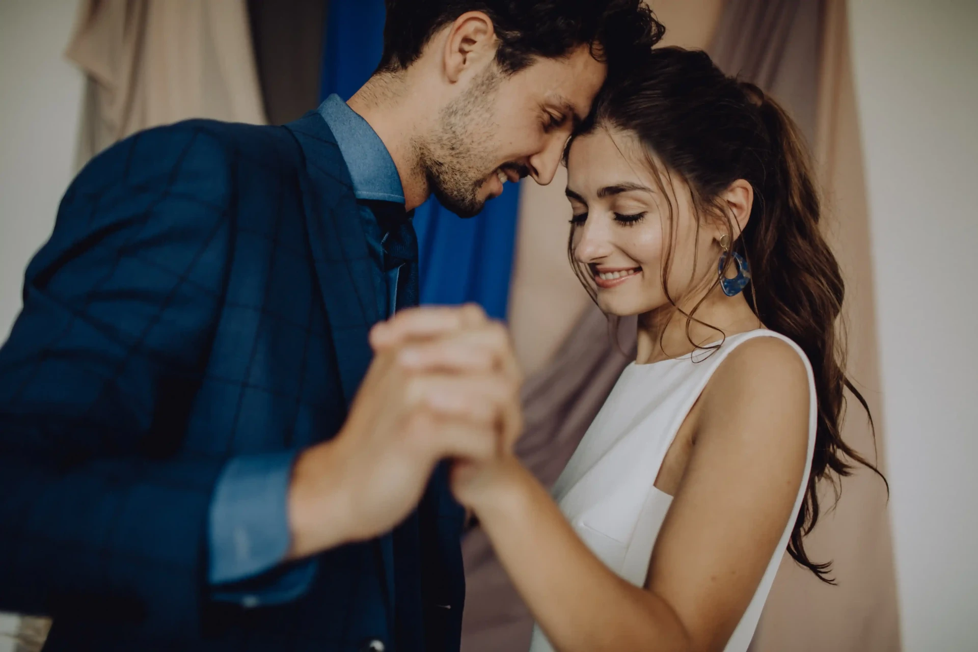 Groom in a blue suit dancing with the bride in a white dress