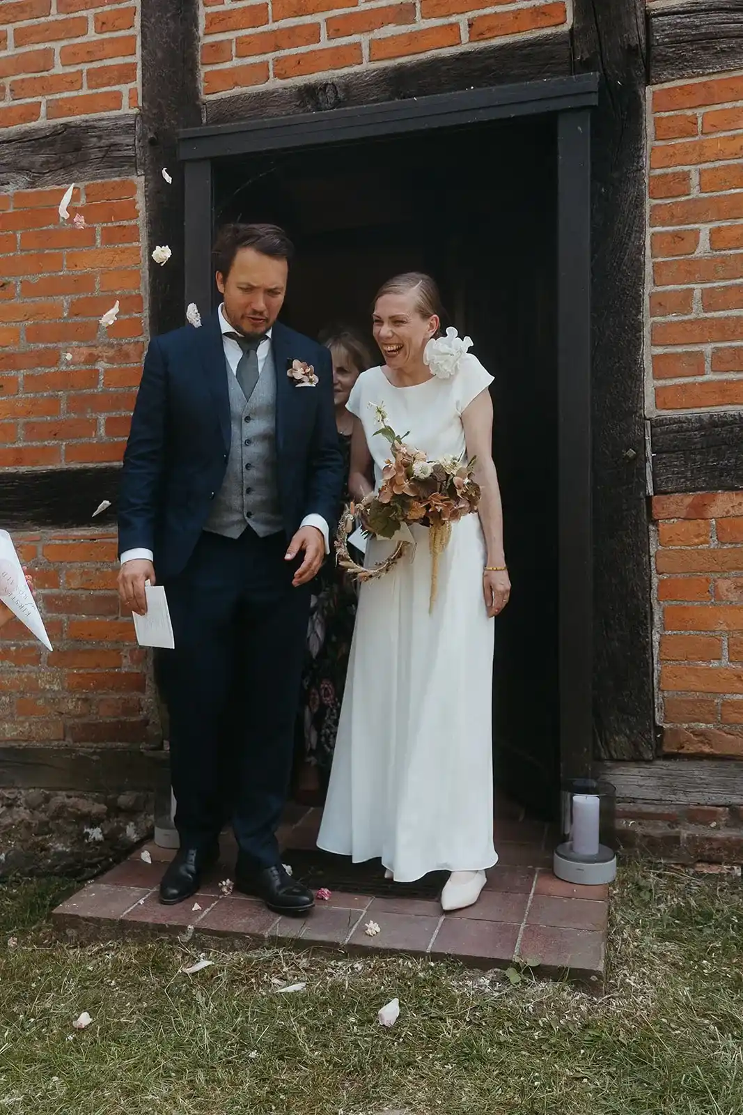 Wedding couple standing in front of an entrance with a dark wooden door