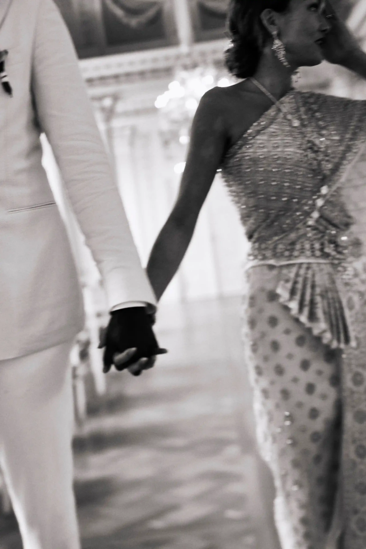 Bride and groom walking hand in hand, photographed from behind