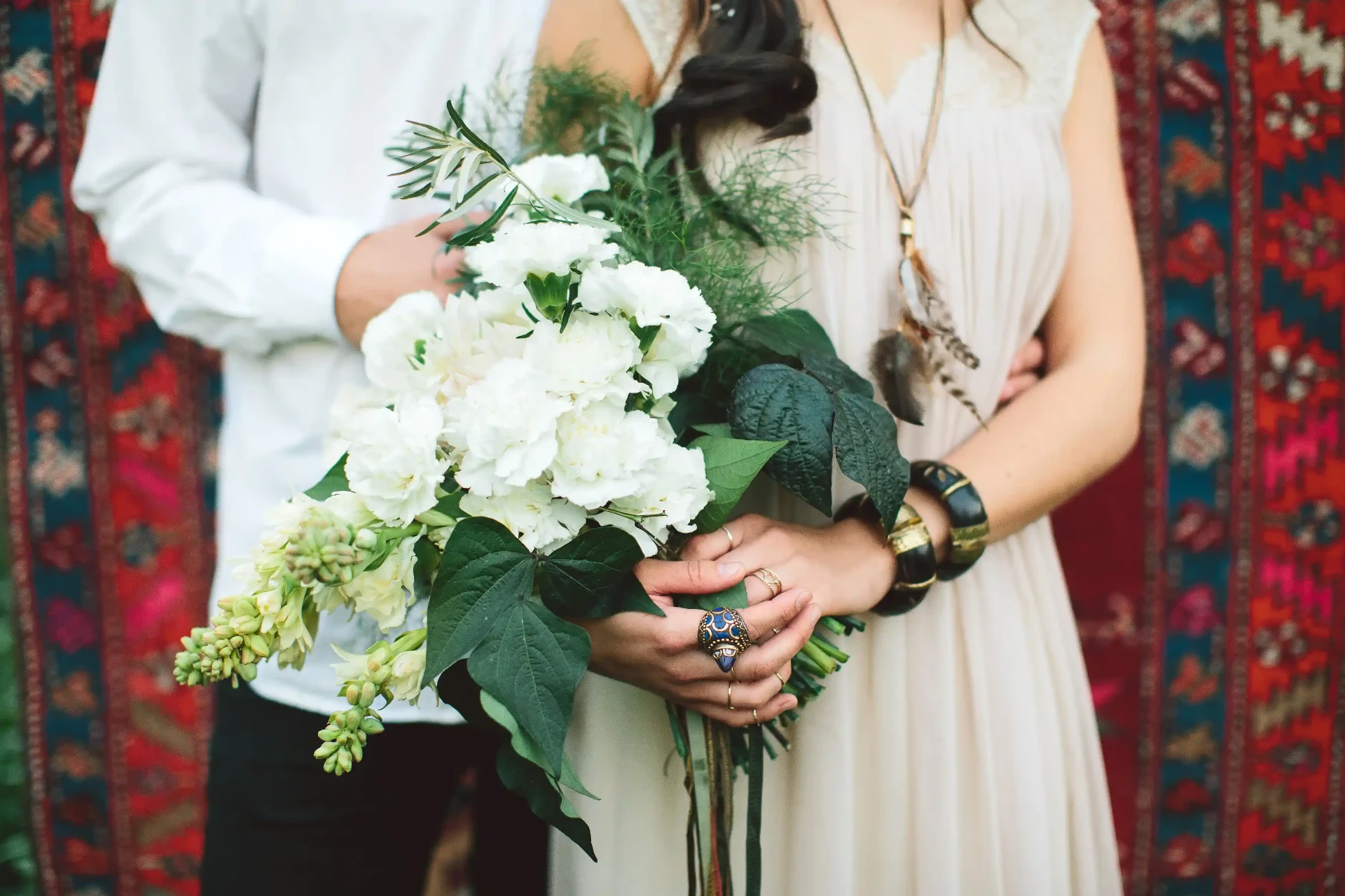 Wedding couple posing in a garden, with the bride holding a white bouquet