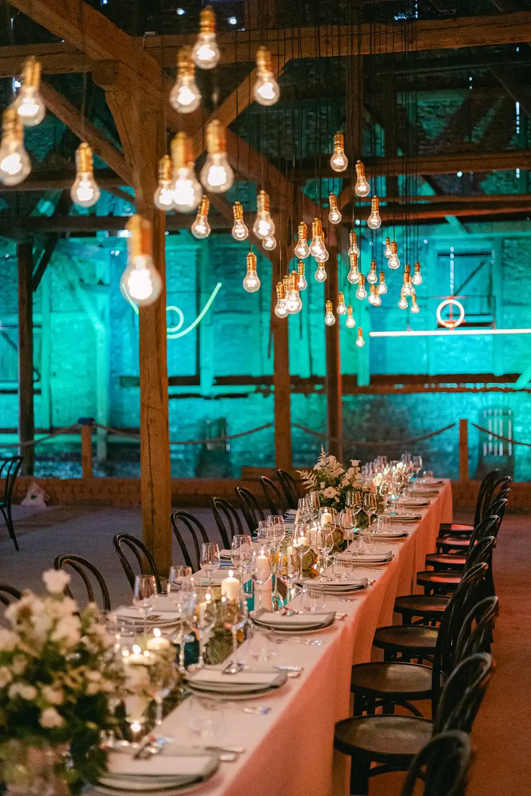 Long wedding table in a barn with turquoise lighting