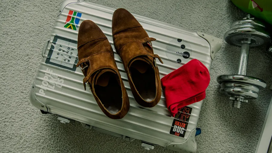 Flat lay of brown leather shoes, red fabric and wedding accessories