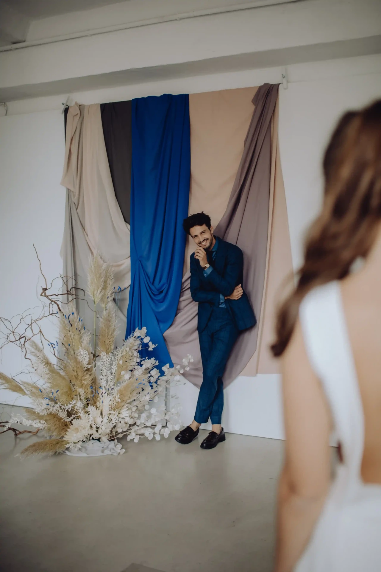 Wedding couple standing in front of blue curtains and white florals