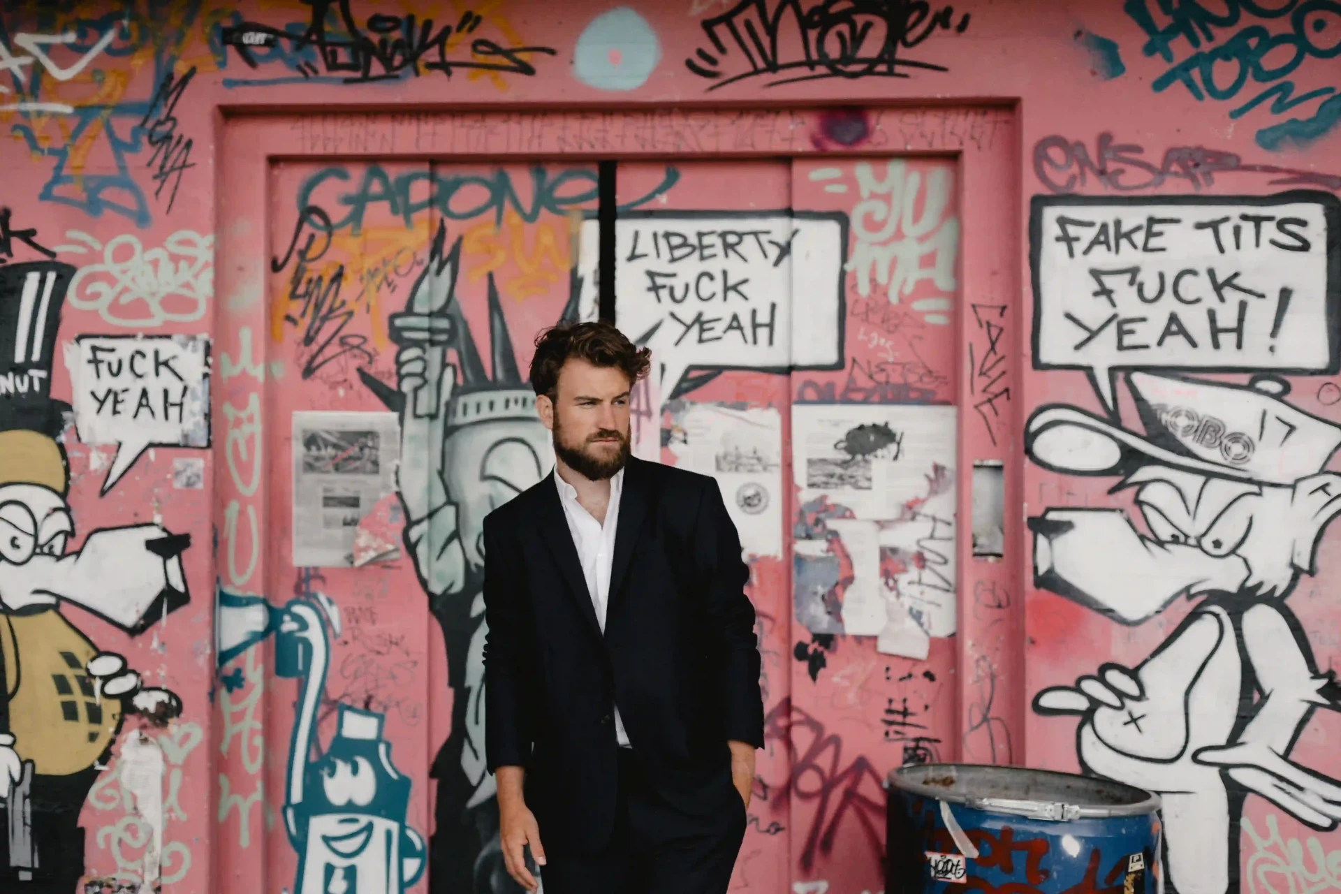Bräutigam in dunklem Anzug vor einer mit Graffiti bemalten Wand