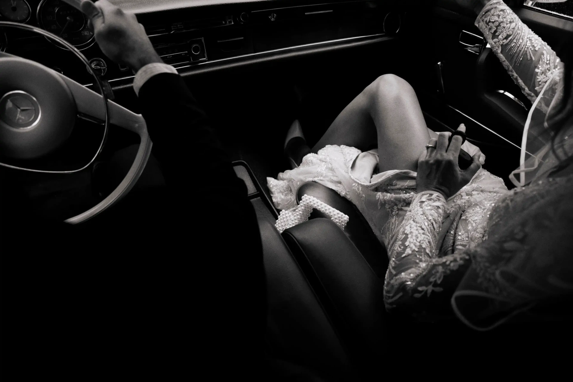 Bride in an embroidered wedding dress sitting in a car