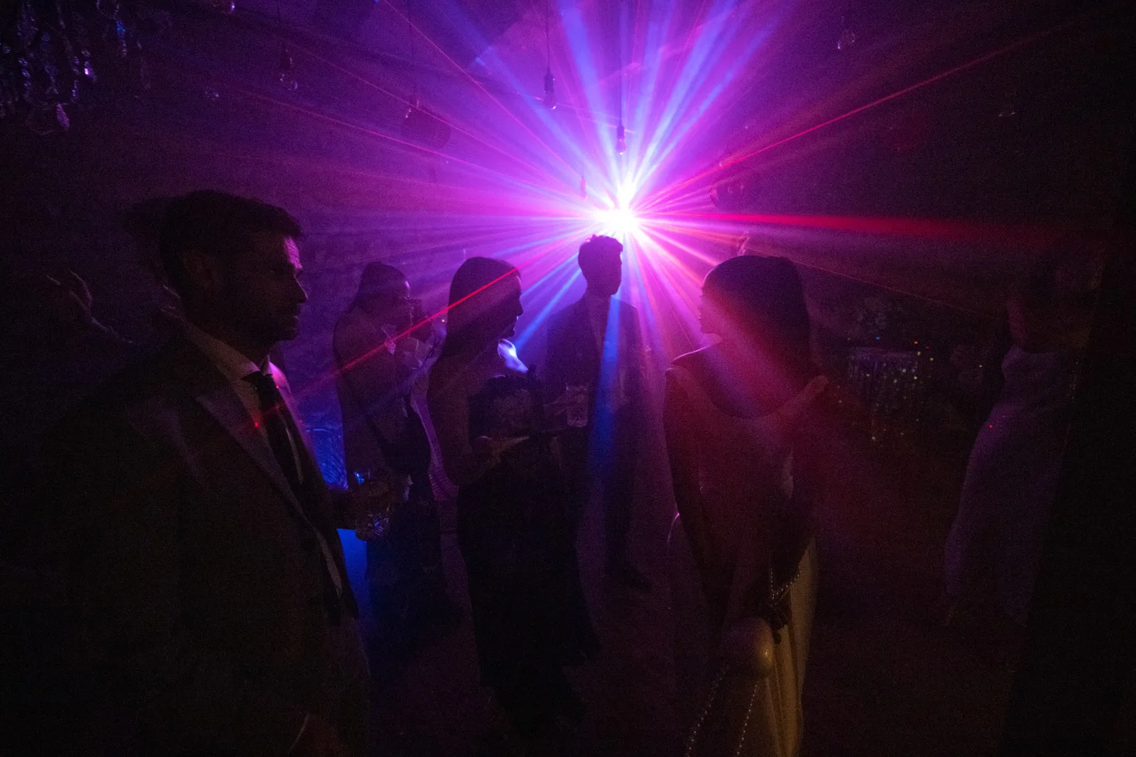 Guests dancing at a wedding celebration under purple stage lighting