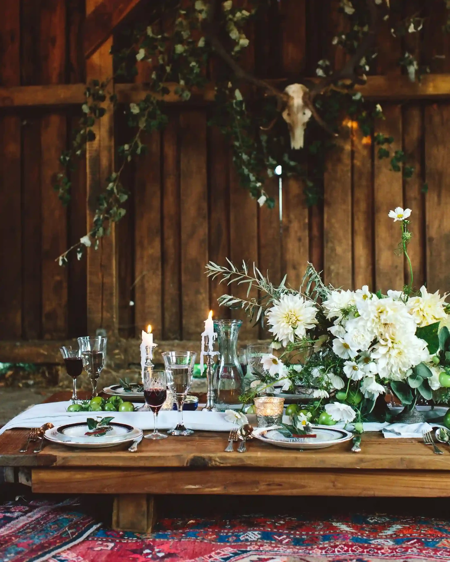 Wedding table with white flowers and candles against a rustic wooden wall