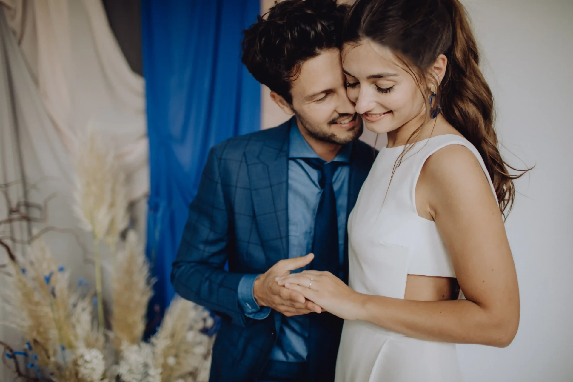 Groom in a blue suit embracing the bride in a white dress