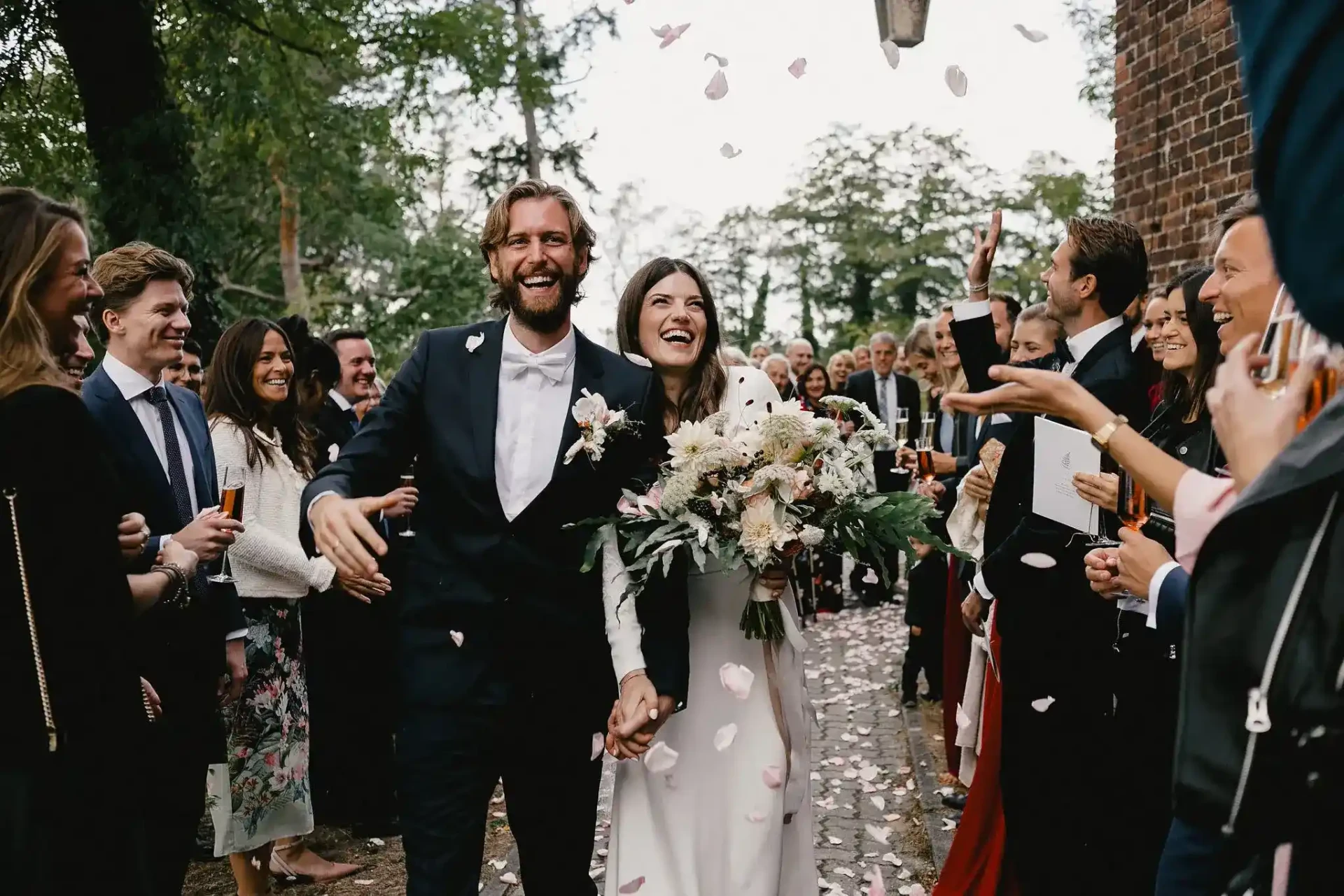 Bride and groom laughing as they walk through cheering guests