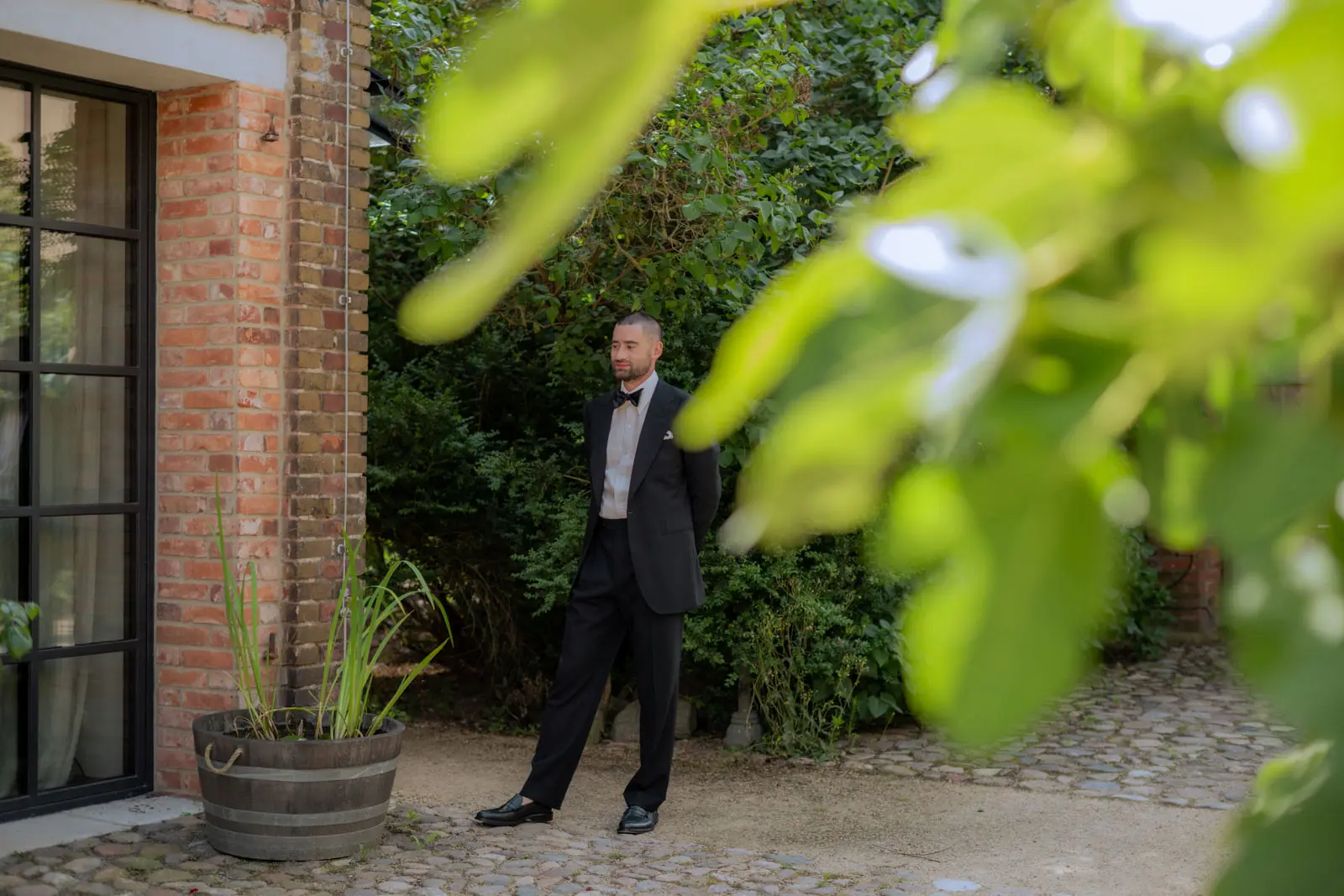 Groom in a black suit outside a brick building