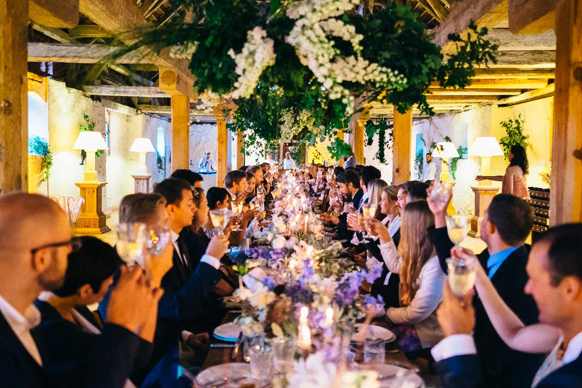 Wedding dinner beneath a floral installation in a rustic venue